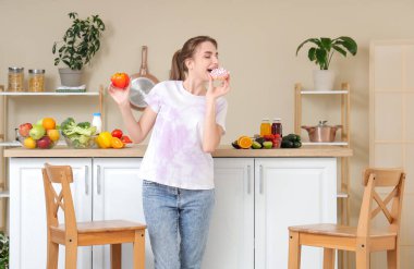 Mutfakta biberli çörek yiyen genç bir kadın. Diyet kavramı