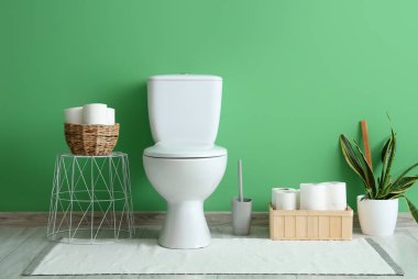 Tuvalet kapağı ve yeşil duvarın yanındaki organizatörlü tuvaletin içinde.