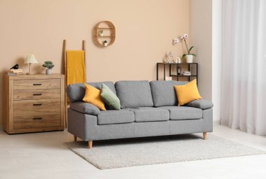 Rahat kanepesi, çiçekleri ve ahşap çekmeceleri olan şık bir oturma odası.