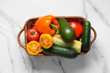 Beyaz arka planda farklı taze sebzelerle dolu bir sepet.