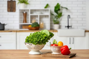 Ahşap mutfak tezgahında taze sebzeli Colander.