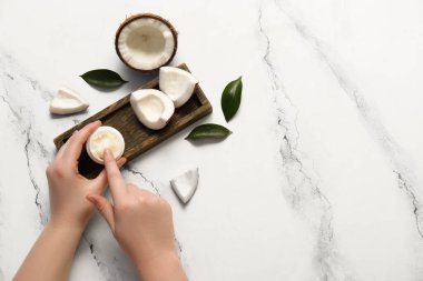 Kavanozda hindistan cevizi ezmeli kadın elleri ve beyaz arka planda taze meyve.