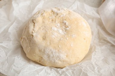 Beyaz arka planda taze hamur içeren fırın kağıdı, yakın plan.