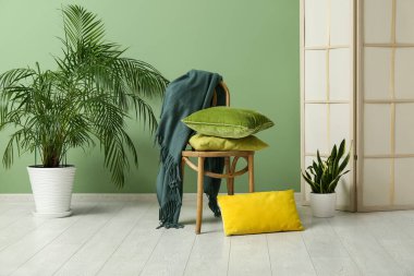 Oturma odasındaki yeşil duvarın yanında yumuşak yastıklı sandalye.