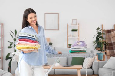 Güzel, genç, mutlu bir kadın. Evde bir yığın elbisesi ve demiri var.