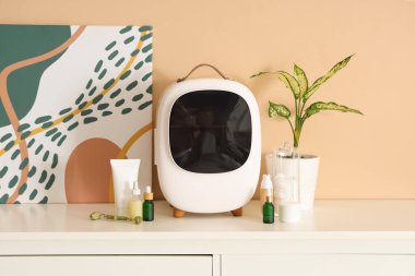 Bej duvarın yanındaki çekmecelerde cilt ürünleri bulunan kapalı küçük kozmetik buzdolabı. Yakın çekim.