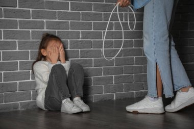 Korkak küçük kız ve annesi gri tuğla duvarın yanında tel örüyorlar. Aile içi şiddet kavramı