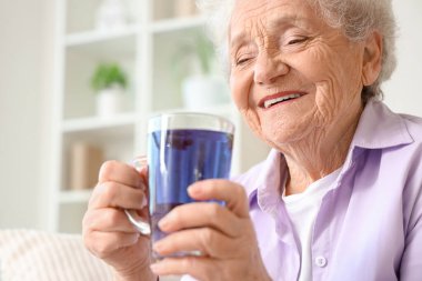 Evde elinde bir bardak kelebek çiçeği çayıyla son sınıf öğrencisi.