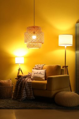 Şık bir oturma odası, rahat sarı koltuğu ve geceleri parlayan lambaları var.