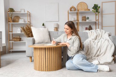 Genç bir kadın evdeki masada yapılacaklar listesi yapıyor.