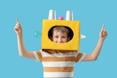 Mavi arka plandaki bir şeyi işaret eden robot kafalı sevimli bir mucit.