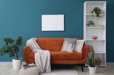 Rahat kahverengi kanepesi, çiçekleri ve mavi duvarın yanında puf olan modern oturma odası.