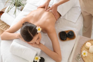 Genç bir kadın spa salonunda terapist tarafından masaj yaptırıyor.