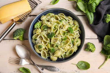 Beyaz ahşap arka planda brokoli ve fesleğen yapraklı enfes conchigile rigate makarnası.