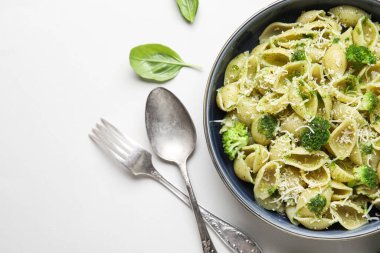Beyaz arka planda brokoli, peynir ve fesleğen yapraklı bir kase lezzetli conchigile rigate makarna.