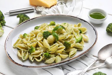 Beyaz ahşap arka planda brokoli ve fesleğen yapraklı enfes konchigile rigate makarna tabağı.