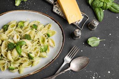 Brokoli ve siyah arka planda fesleğen yapraklı lezzetli koni rigli makarna tabağı.