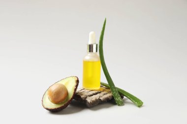 Kozmetik ürün şişesi, ağaç kabuğu, avokado ve aloe vera yaprakları beyaz arka planda, yakın plan