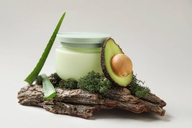 Beyaz arka planda kozmetik ürün kavanozu, ağaç kabuğu, yosun ve malzemelerle kompozisyon, yakın plan