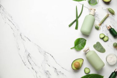 Kozmetik ürünleri şişeleri, yüz masajı aletleri ve mermer arka plandaki malzemelerle kompozisyon