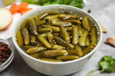 Lezzetli salatalıklı kase ve gri arka planda farklı baharatlar, yakın plan.