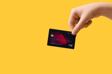 Sarı arka planda kredi kartı olan bir kadın.