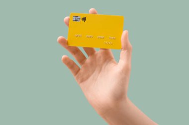 Hafif turkuaz arka planda kredi kartı olan bir kadın, yakın plan.