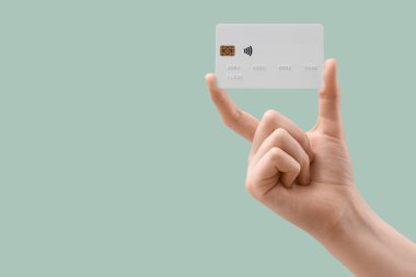 Hafif turkuaz arka planda kredi kartı olan bir kadın, yakın plan.