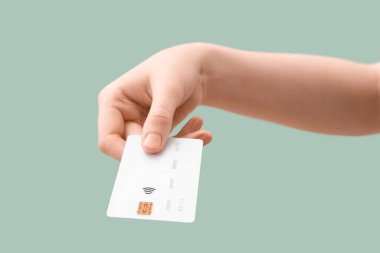 Hafif turkuaz arka planda kredi kartı olan bir kadın, yakın plan.