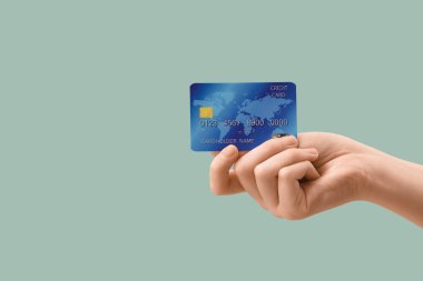 Hafif turkuaz arka planda kredi kartı olan bir kadın, yakın plan.