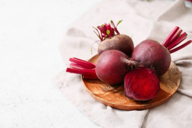 Beyaz arka planda taze pancar kökleri olan ahşap bir tabak.