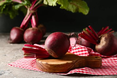 Gri masa üzerinde taze pancar kökü olan ahşap tahta bir tahta.