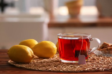 Evdeki ahşap masada bir fincan sıcak aromatik çay, limon ve şeker.