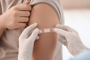 Klinikte aşıdan sonra doktor yaması uygulayan genç adam, yakın plan.