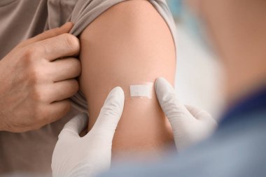 Klinikte aşıdan sonra doktor yaması uygulayan genç adam, yakın plan.