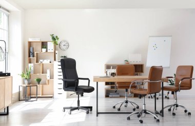 Konferans salonunun içinde masa, raf üniteleri ve bitkiler var.