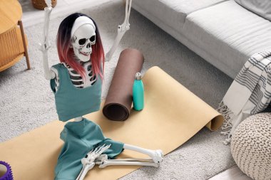 Oturma odasındaki spor kıyafetleri ve peruğu olan insan iskelet modeli.