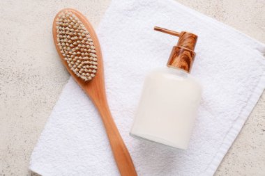 Beyaz grunge arka planda masaj vücut fırçası, havlu ve bir şişe kozmetik ürünü ile kompozisyon, yakın plan.