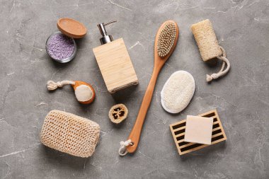 Gri grunge arka planda masaj vücut fırçaları, süngerler ve bir şişe kozmetik ürünü içeren kompozisyon