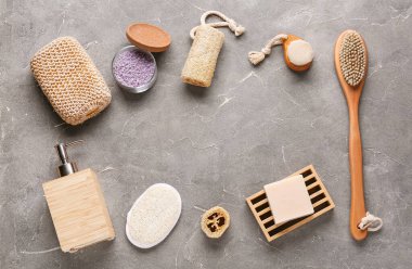 Gri grunge arka planda masaj vücut fırçaları, süngerler ve kozmetik ürünlerden oluşan çerçeve