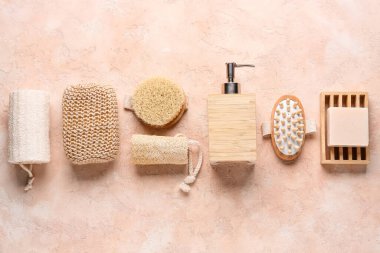 Masaj vücut fırçaları, süngerler ve pembe grunge arka planda bir şişe kozmetik ürünle kompozisyon