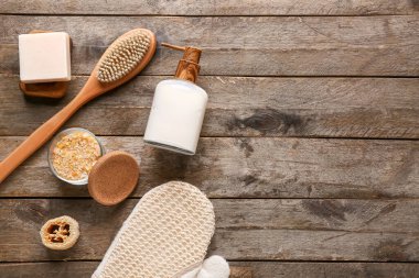 Masaj fırçası, eldiven, sabun ve ahşap zemin üzerinde deniz tuzu olan kase.