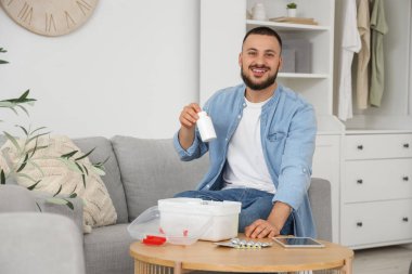 Genç adam evdeki ilk yardım çantasından hap alıyor.