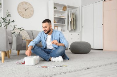 Genç adam evdeki ilk yardım çantasından hap alıyor.