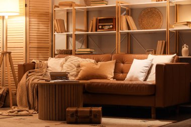 Kitaplığı, kanepesi ve masası olan oturma odasının içinde.