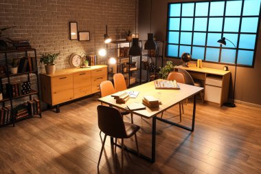 Geceleri kitap rafları, masalar ve parlayan lambalarla dolu karanlık bir oda.