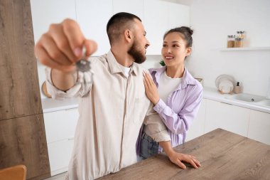 Mutfaktaki yeni dairesinden anahtarı olan genç bir çift.