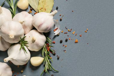 Taze sarımsak ve gri arka planda farklı baharatlar.