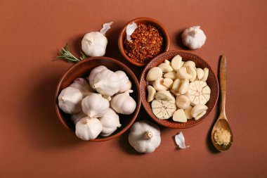 Kahverengi arka planda taze sarımsaklı kaseler ve biberiye.