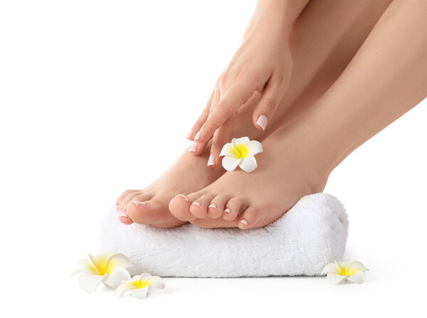Feet of young woman with fresh pedicure, towel and flowers isolated on white background, closeup